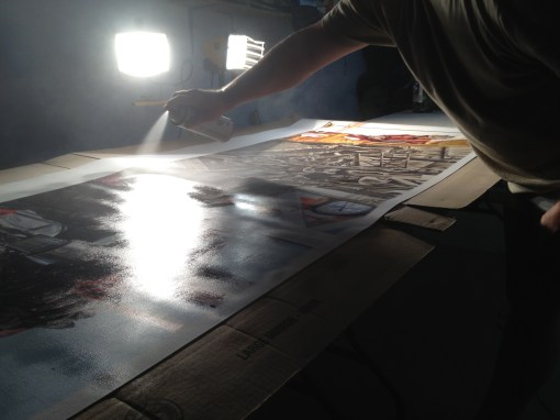 Spraying not one, but two cans of museum-quality archival laminate onto the canvas in the garage. It sure dries a lot faster in this weather than at Christmas time.